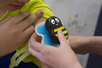 nurse puts bumble bee patch on child's arm